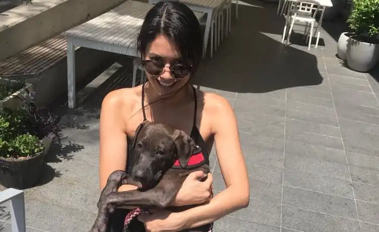 Melanie Perkins sentada con un perro en una fotografía al aire libre
